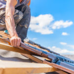 Roofer installing shingles on a house roof.