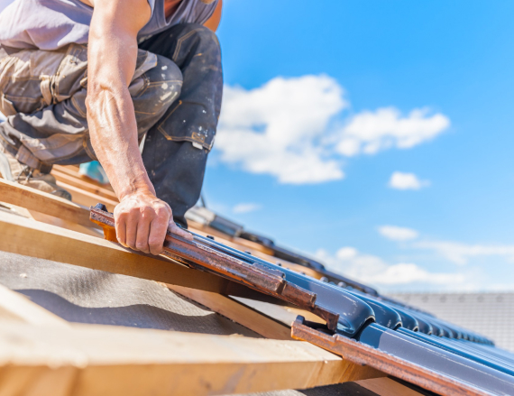 Roofer installing shingles on a house roof.
