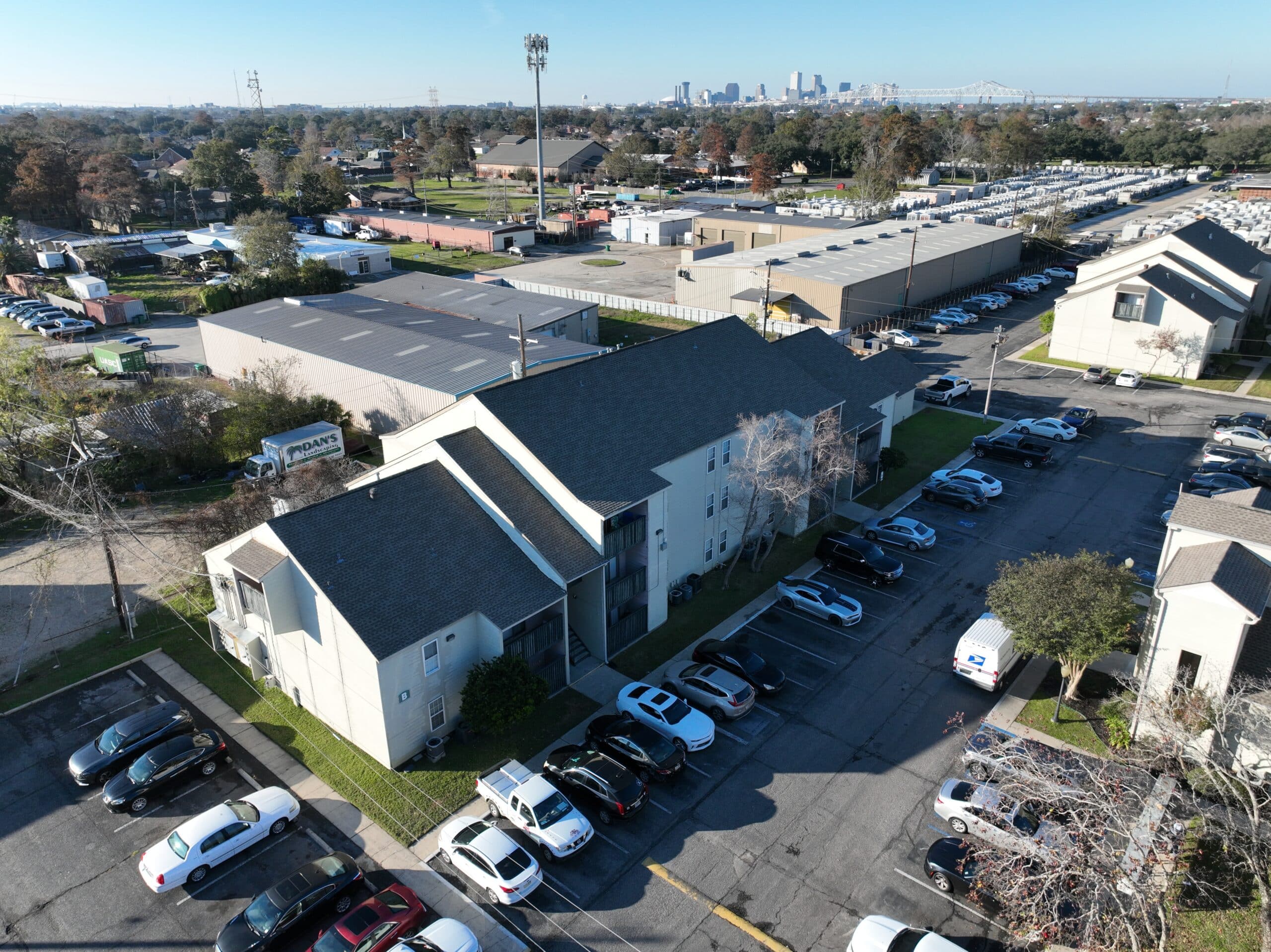Aerial view of an apartment complex with multiple parked cars along the street and in designated parking areas.